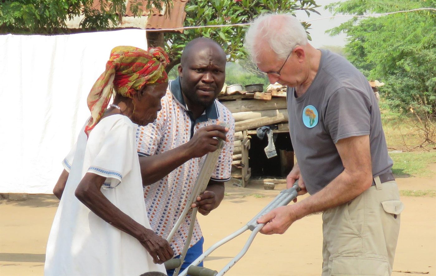 A club volunteer fits donated crutches for a woman as part of Crutches 4 Africa