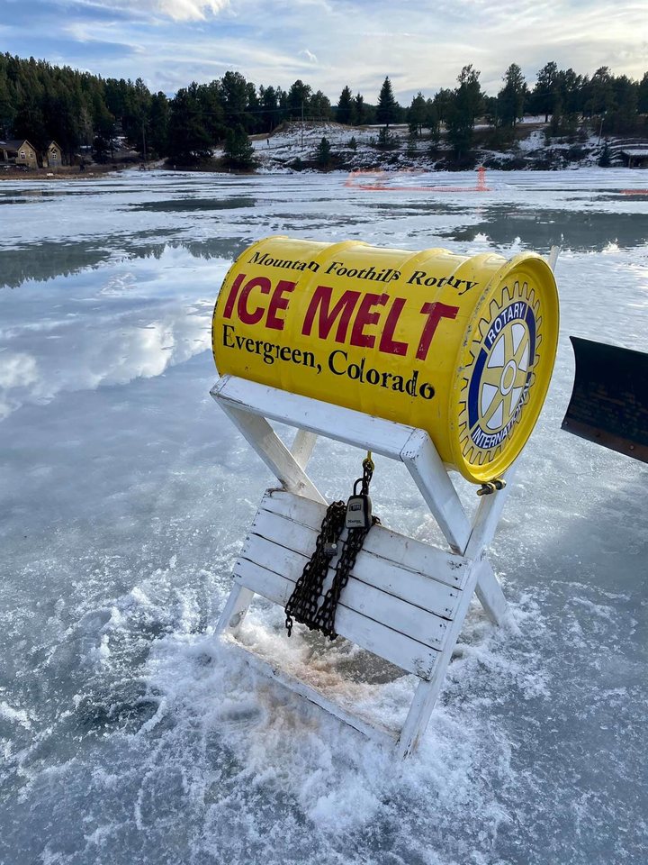 The yellow Mountain Foothills Rotary Ice Melt barrel on its stand, out on the melting ice of Evergreen Lake